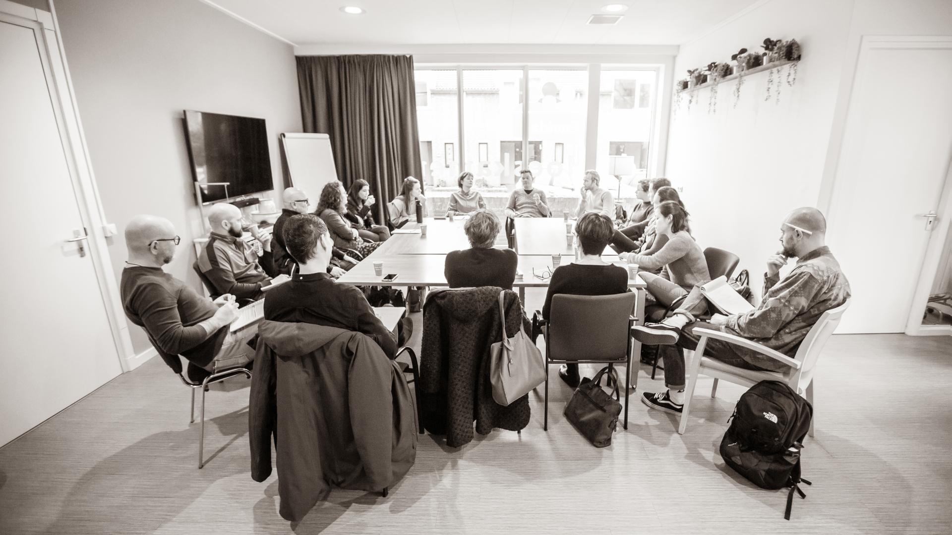 Groep mensen vergaderen om grote tafel