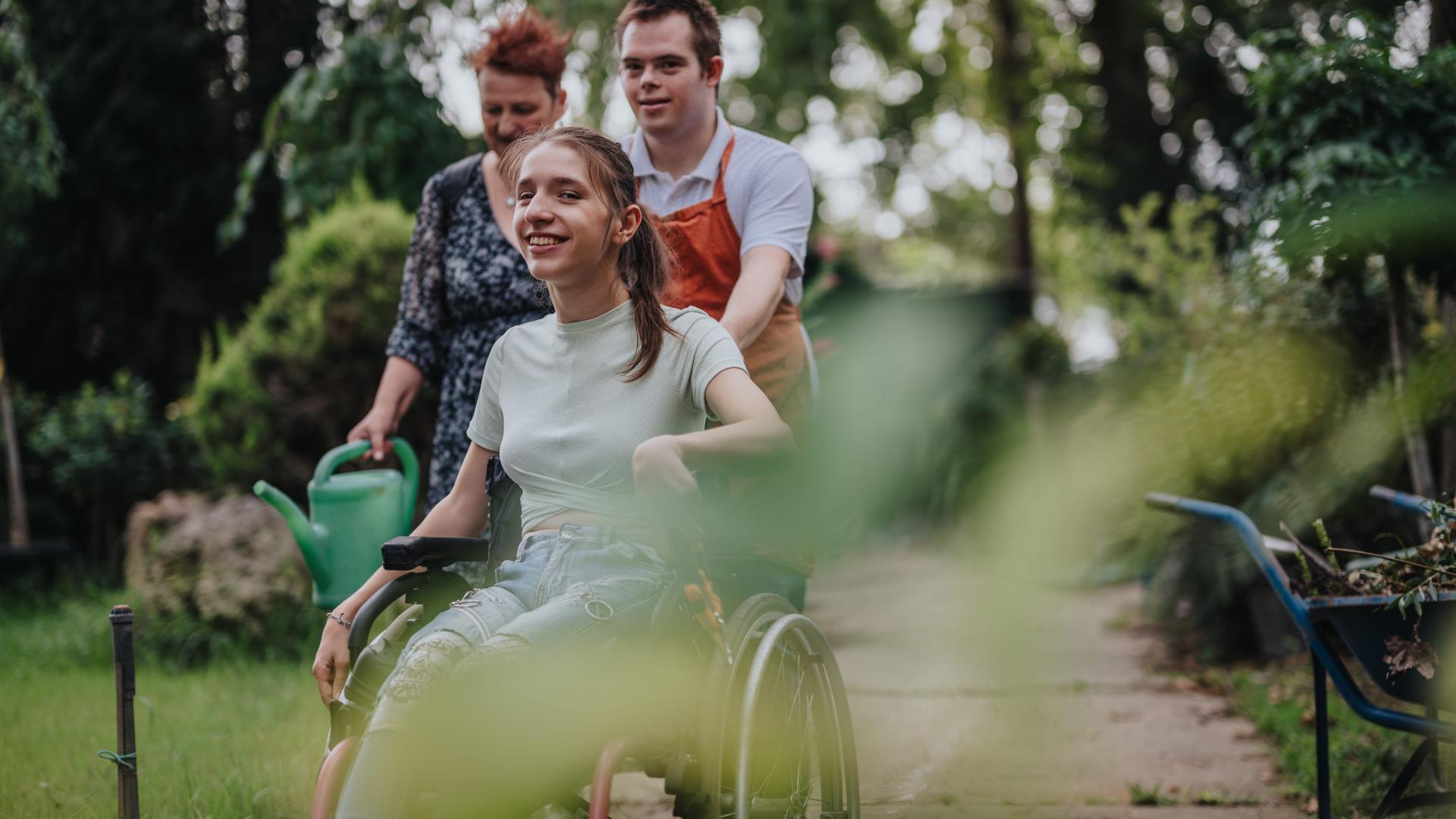 Drie mensen, een duwt een persoon in een rolstoel