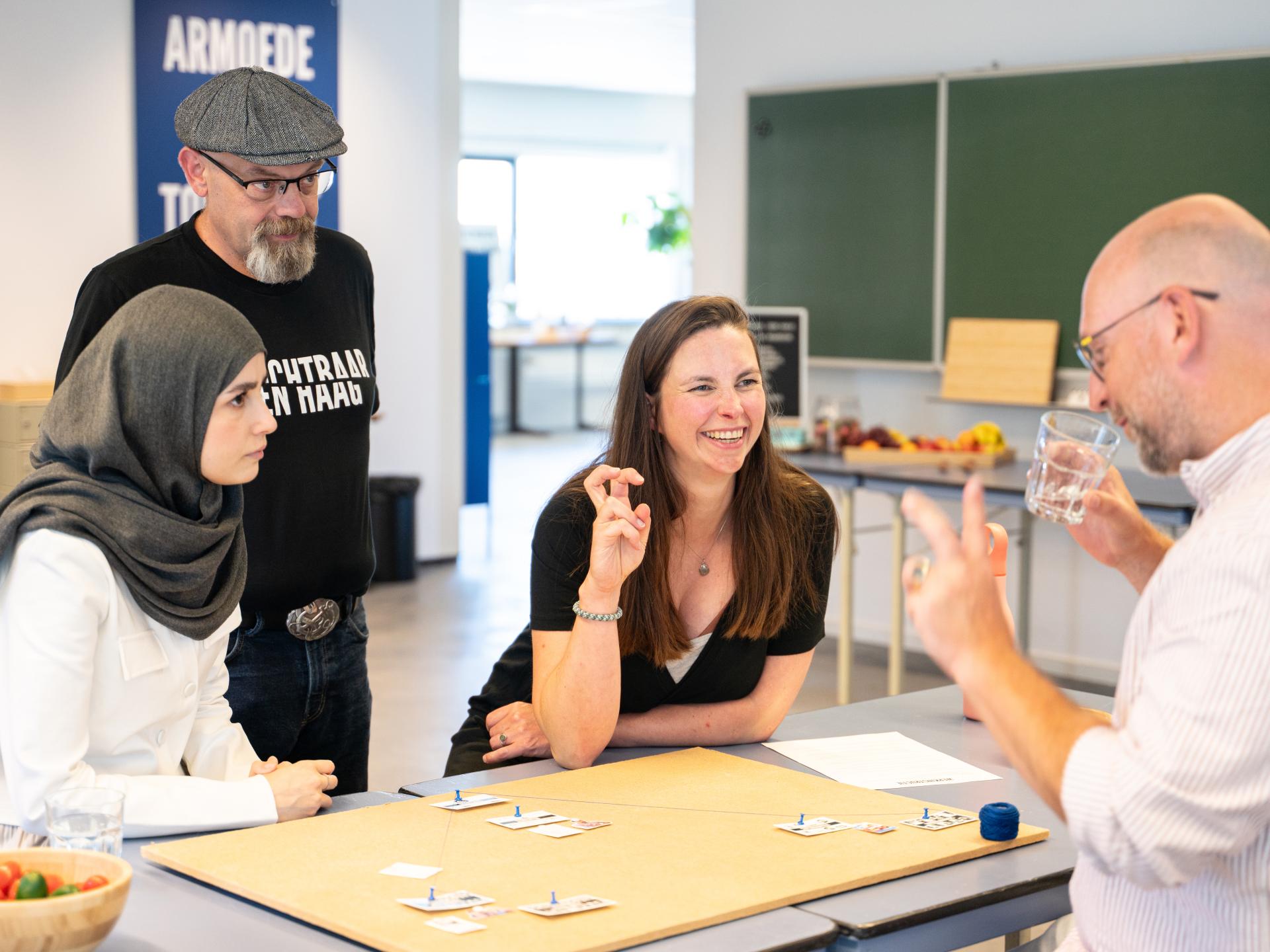 Vier mensen rond kaartjes aan tafel